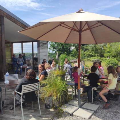 Vue sur la terrasse de la Cantine où des personnes prennent des consommations