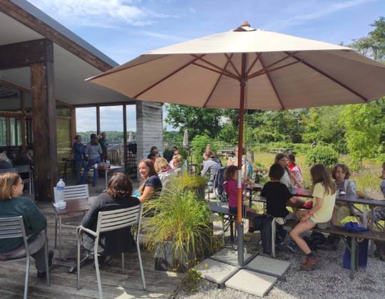 Vue sur la terrasse de la Cantine où des personnes prennent des consommations