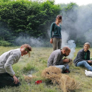 Quatre personnes essayant d'allumer un feu dans la nature