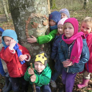 Un groupe d'enfant avec une oeuvre d'art réaliser avec de l'argile sur un arbre